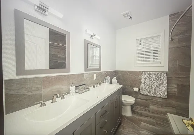 a bathroom with a double vanity sink toilet and a mirror