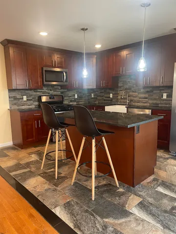 a kitchen with kitchen island granite countertop a sink a counter top space cabinets and stainless steel appliances
