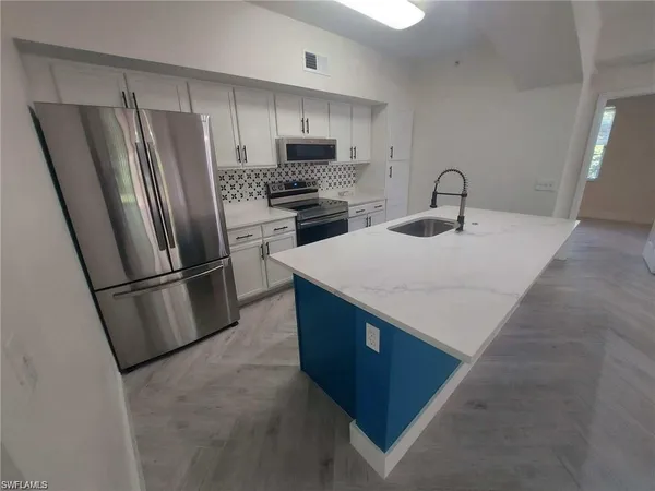 a kitchen with stainless steel appliances a refrigerator a stove a sink and a refrigerator