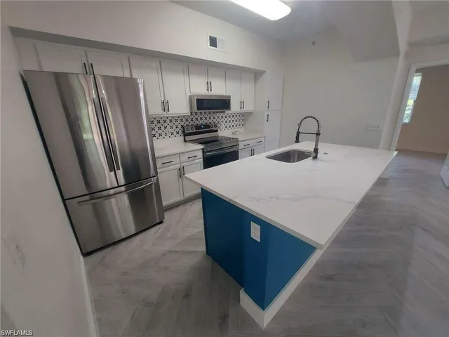 a kitchen with stainless steel appliances a refrigerator a stove a sink and a refrigerator