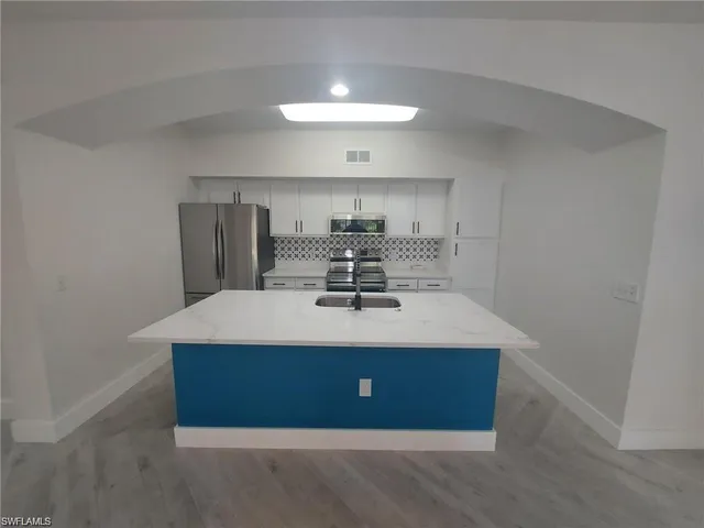 a view of kitchen with kitchen island a sink wooden floor and living room view