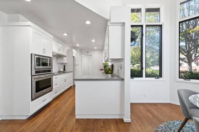 a kitchen with stainless steel appliances a microwave a stove and white cabinets with wooden floor