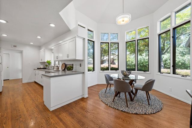 a kitchen with kitchen island granite countertop a stove a sink a refrigerator a dining table and chairs with wooden floor