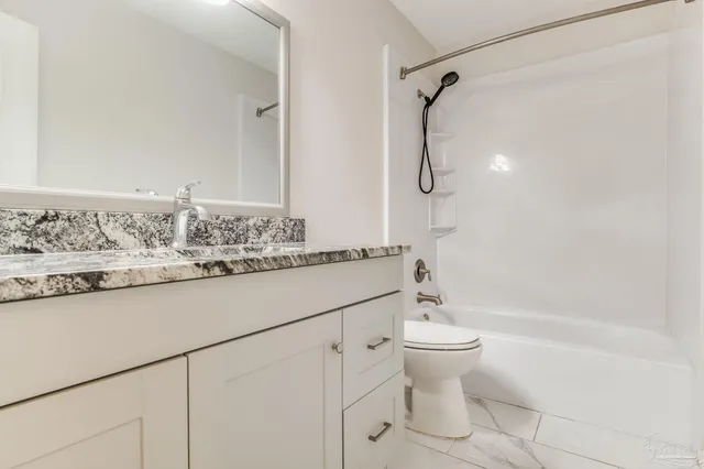 a bathroom with a granite countertop sink a toilet and shower