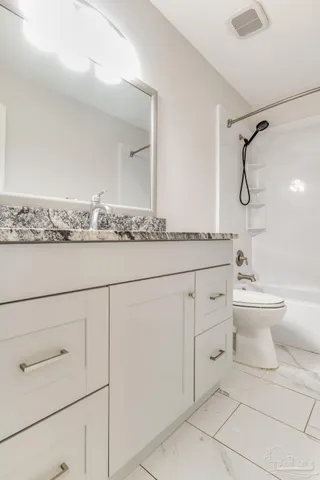 a bathroom with a granite countertop sink mirror vanity and toilet