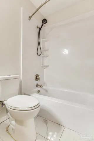 a white toilet sitting next to a bath tub and a shower
