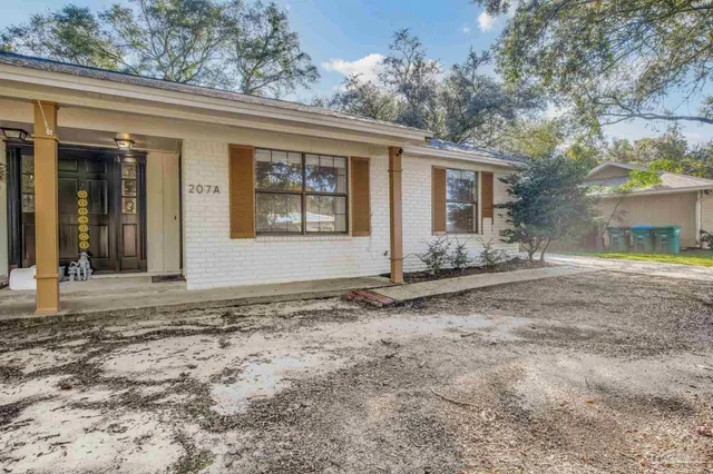 a view of a house with a yard and large tree