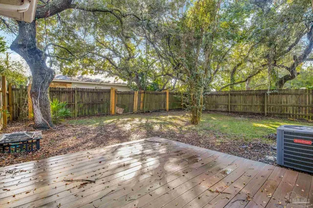 a view of a backyard with large trees and wooden fence