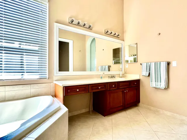 a spacious bathroom with a tub sink and mirror
