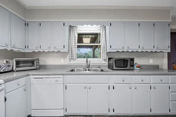 a kitchen with granite countertop white cabinets and white appliances