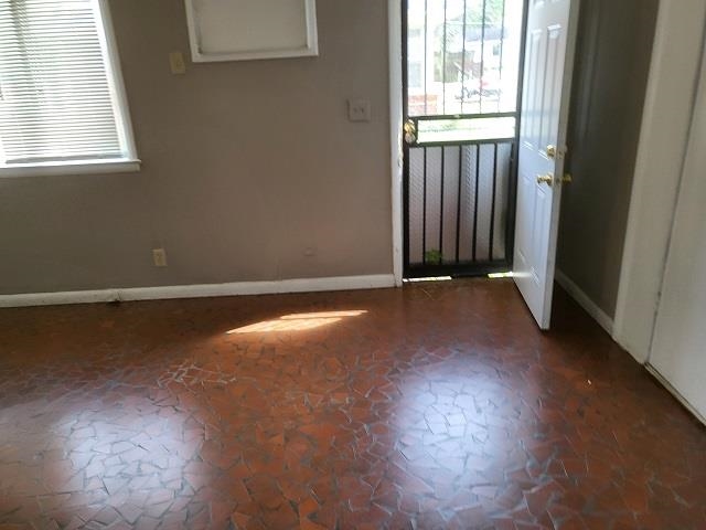 4985 Millbranch Road Memphis, TN 38116 - Photo 3 of 8 an empty room with wooden floor and windows with curtains