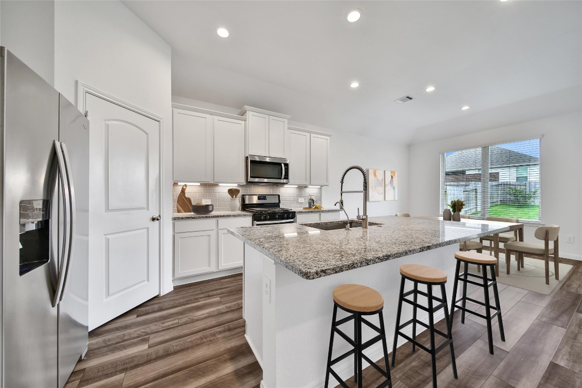 906 Youth Water Road Montgomery, TX 77316 - Photo 12 of 42 a kitchen with stainless steel appliances granite countertop a stove a sink a refrigerator with white cabinets and wooden floor
