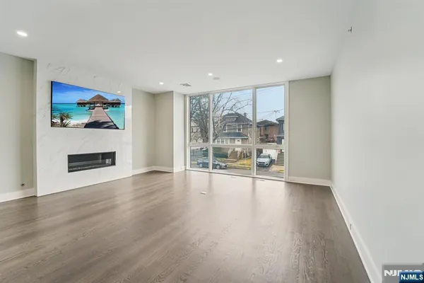 a view of an empty room with a window and wooden floor