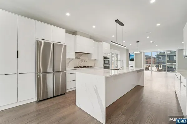 a kitchen with stainless steel appliances a refrigerator sink and wooden floor