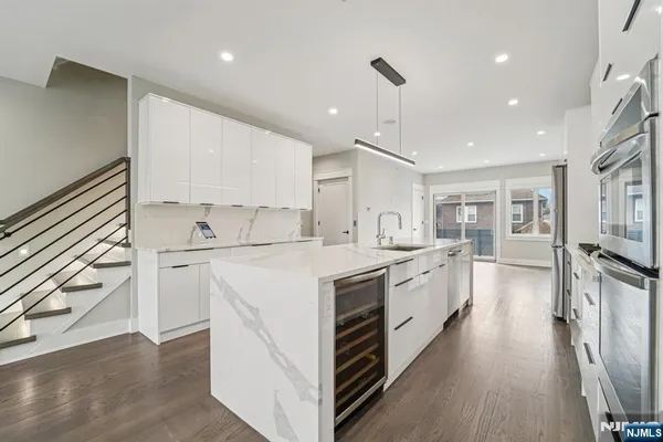 a large kitchen with kitchen island wooden floors white cabinets and stainless steel appliances