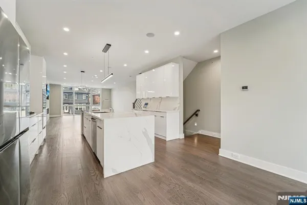a view of a kitchen with kitchen island wooden floors appliances and cabinets