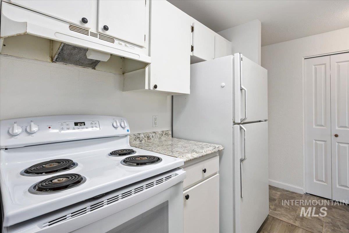 259 Pheasant Road, Unit 83 Twin Falls, ID 83301 - Photo 9 of 26 White electric range with overhead exhaust hood, white upper and lower cabinetry, laminate countertops, and a white refrigerator