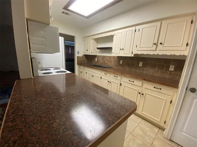a kitchen with granite countertop a sink a stove and cabinets