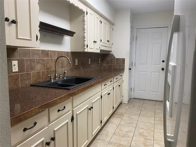 a kitchen with stainless steel appliances a sink dishwasher refrigerator and cabinets