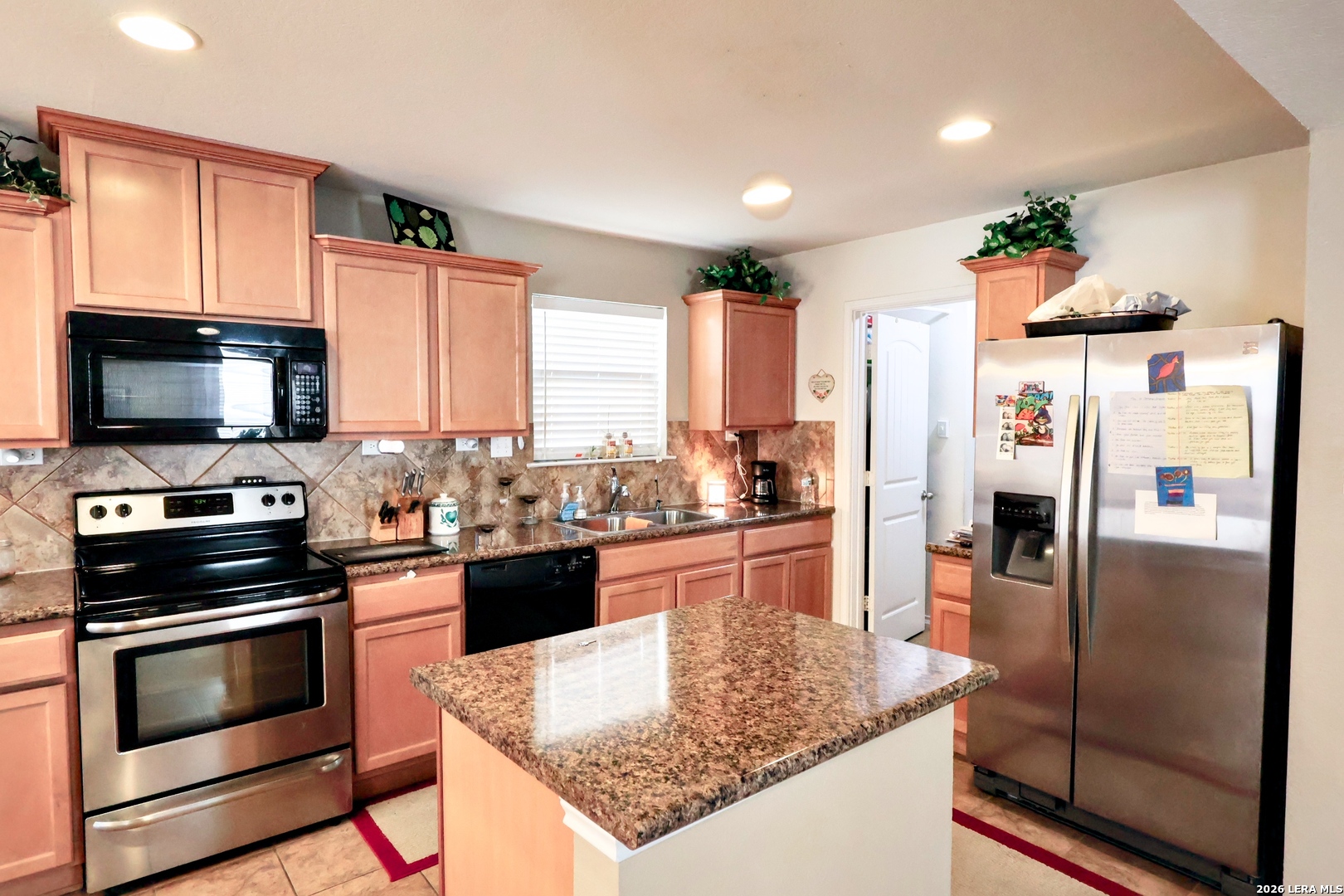 9927 Hawk Village Converse, TX 78109 - Photo 11 of 25 a kitchen with granite countertop a refrigerator stove and microwave