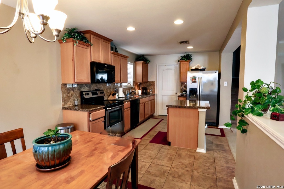 9927 Hawk Village Converse, TX 78109 - Photo 10 of 25 a kitchen with stainless steel appliances kitchen island granite countertop a stove a sink dishwasher a dining table and chairs with wooden floor