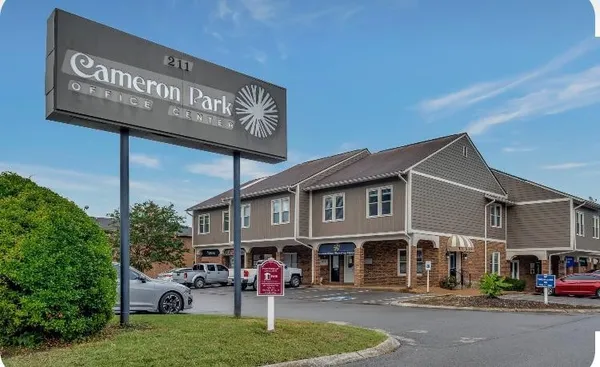 a front view of a building with lots of trees and plants