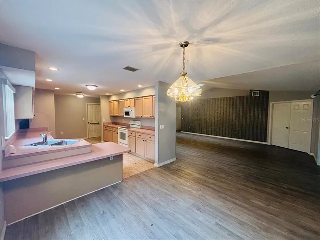 a large kitchen with kitchen island a stove a sink dishwasher and white cabinets with wooden floor