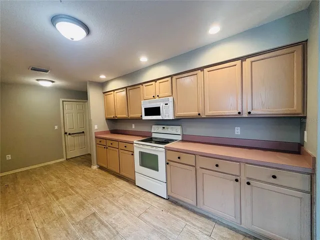 a kitchen with white cabinets stainless steel appliances a sink and a window