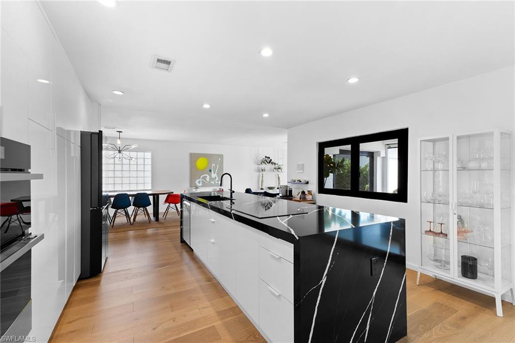 70 Thorncrest Lane Naples, FL 34113 - Photo 11 of 50 a dining hall with stainless steel appliances granite countertop a couch and a dining table with wooden floor