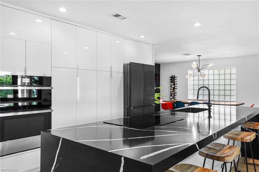 70 Thorncrest Lane Naples, FL 34113 - Photo 14 of 50 a kitchen with stainless steel appliances kitchen island granite countertop a refrigerator a stove and a sink with wooden floor