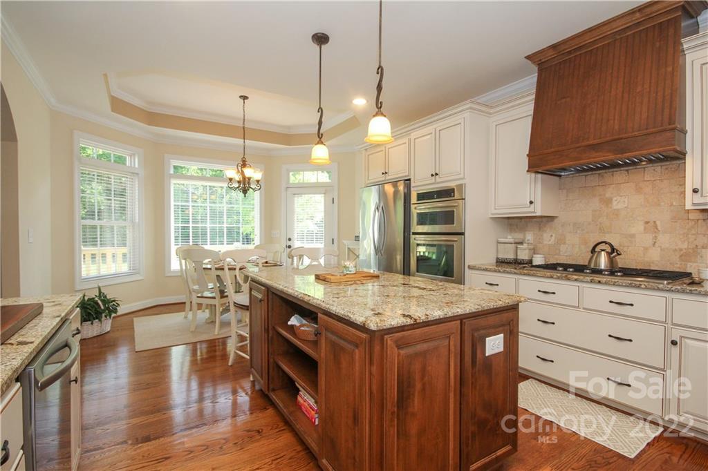 159 Abbington Place, Unit 16 Locust, NC 28097 - Photo 14 of 47 a open kitchen with stainless steel appliances granite countertop a stove a refrigerator a sink dishwasher and white cabinets with wooden floor