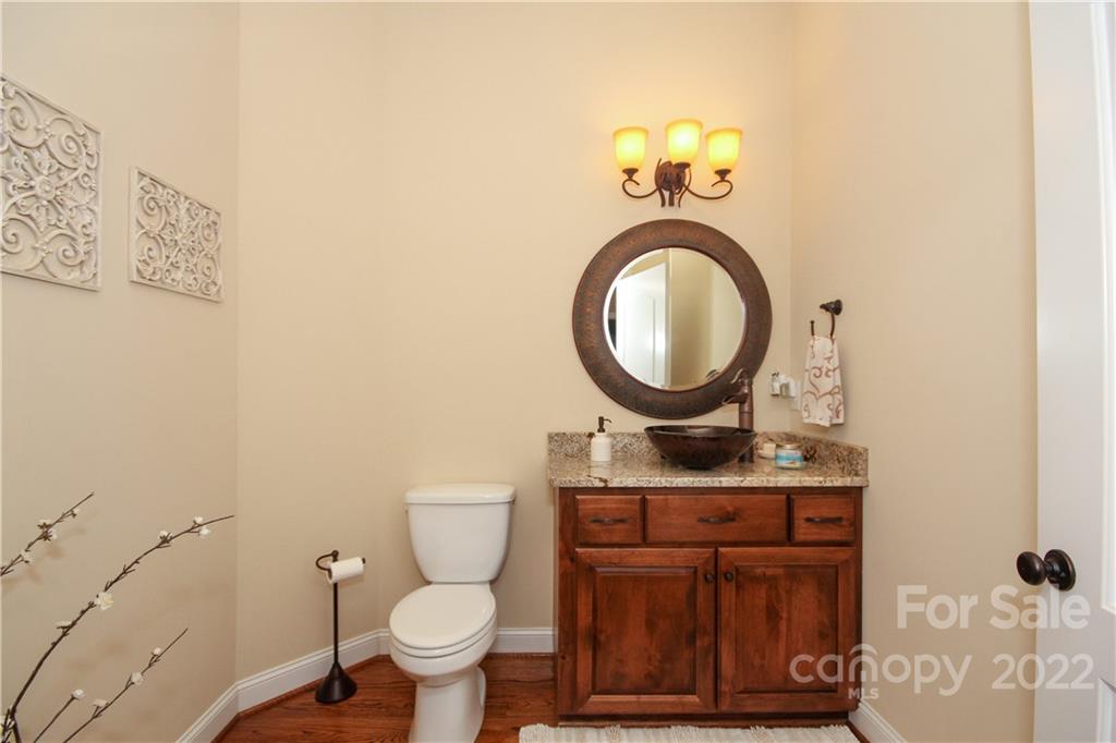 159 Abbington Place, Unit 16 Locust, NC 28097 - Photo 9 of 47 a bathroom with a granite countertop toilet a sink and a mirror