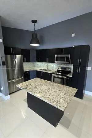 a kitchen with stainless steel appliances a refrigerator a stove a sink a oven with a dining table and chairs