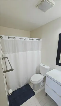 a white toilet sitting next to a white sink and vanity