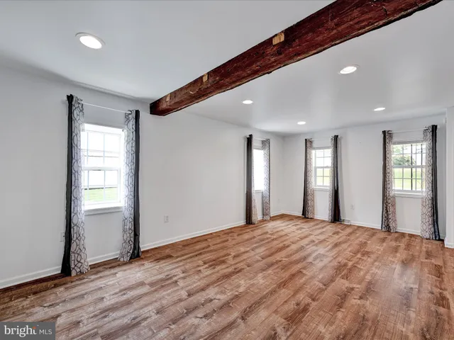 a large bedroom with wooden floor and windows
