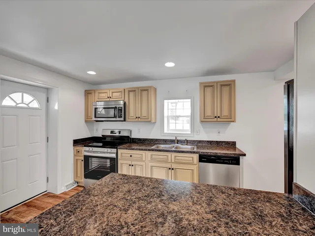 a kitchen with stainless steel appliances granite countertop a stove a sink and a refrigerator