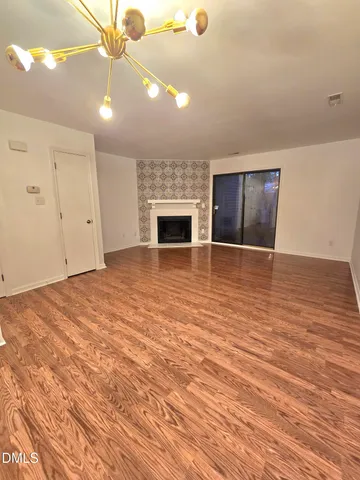 an empty room with wooden floor fan and window