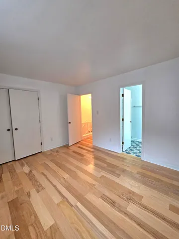 a view of an empty room with wooden floor and window