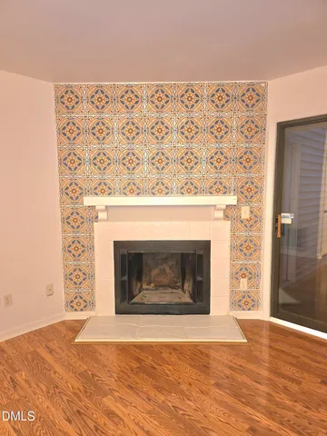 a view of wooden floor a fireplace and windows in a room