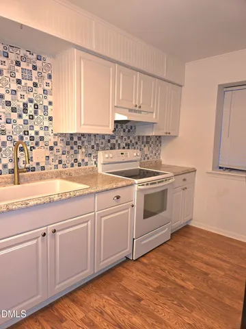a kitchen with granite countertop white cabinets and white appliances