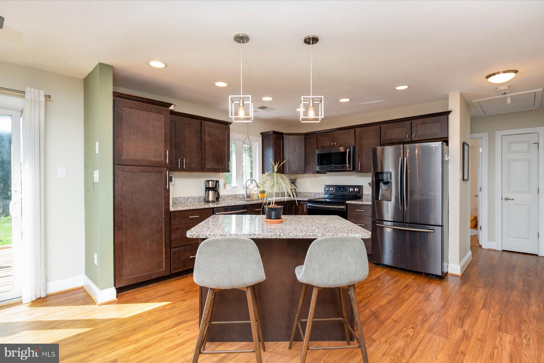 213 Old Magothy Bridge Road Pasadena, MD 21122 - Photo 10 of 31 a kitchen with stainless steel appliances granite countertop a refrigerator a stove a sink dishwasher a dining table and chairs with wooden floor