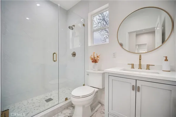 a bathroom with a toilet sink vanity granite and shower