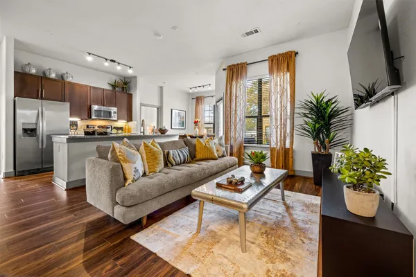 a living room with furniture potted plant and kitchen view