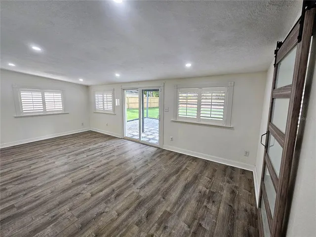 a view of an empty room with a window and wooden floor