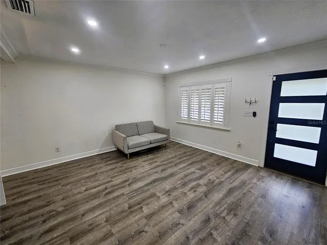 a view of an empty room with a window and wooden floor