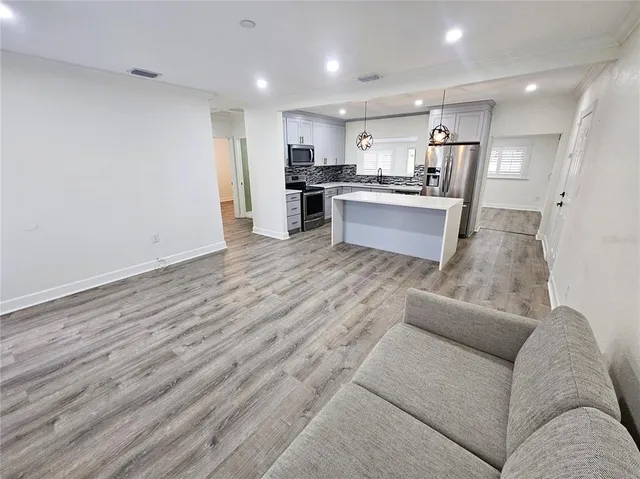 a large living room with stainless steel appliances granite countertop a couch and a fireplace