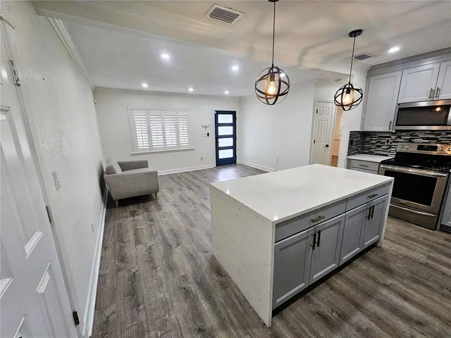 a kitchen that has a lot of cabinets and wooden floor