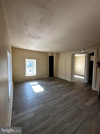 a view of empty room with window and wooden floor