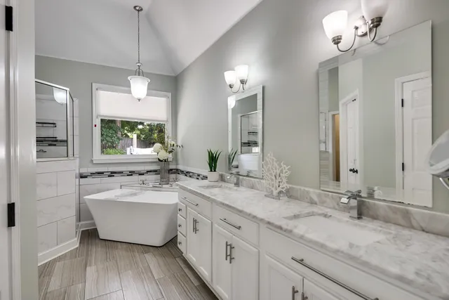 a spacious bathroom with a double vanity sink mirror and bathtub