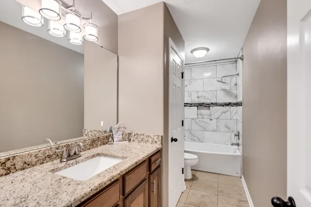 a bathroom with a granite countertop sink a toilet and shower
